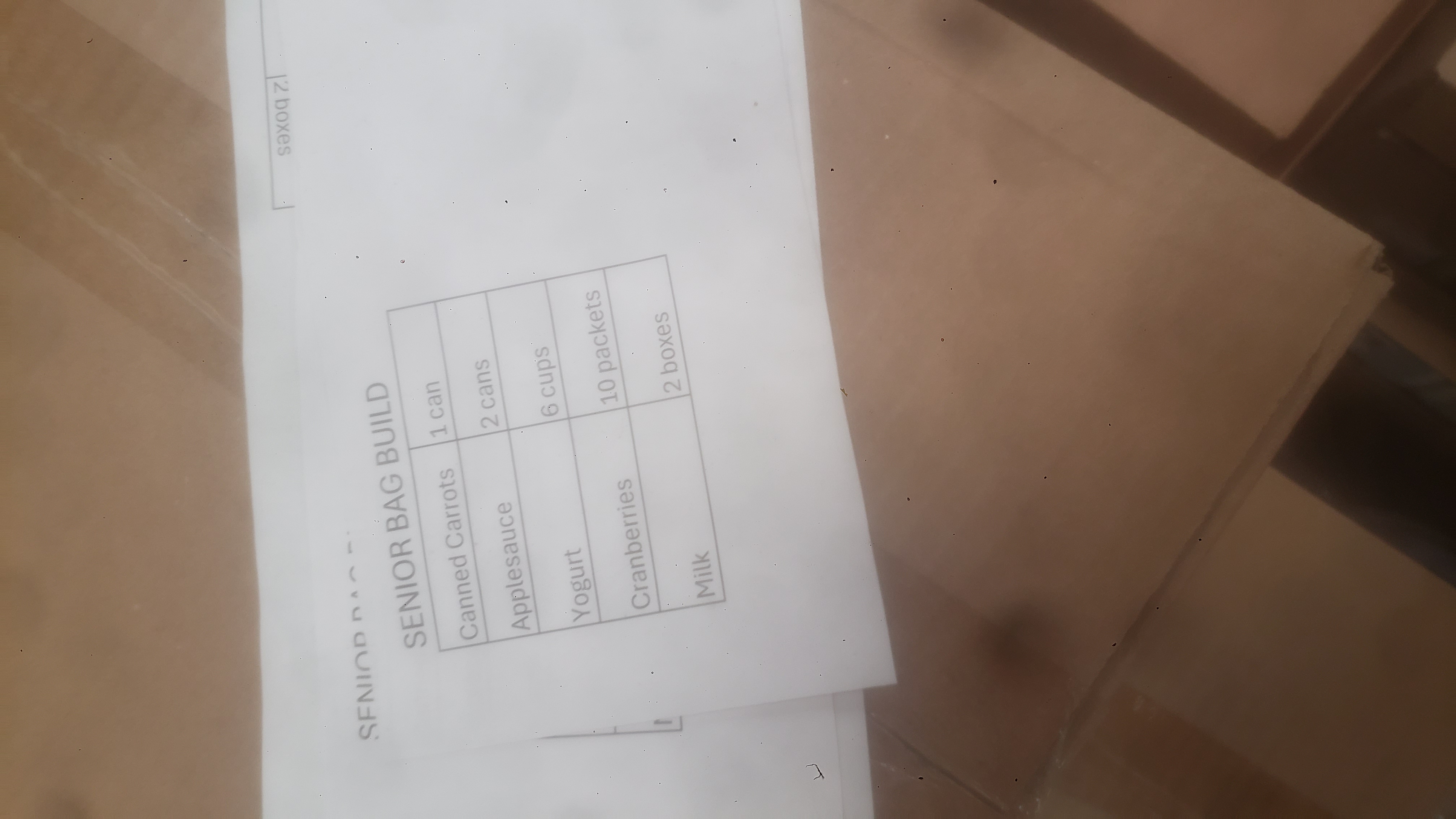 A table on a piece of paper titled senior bag build and lists a list of food items and their required quantities per bag.